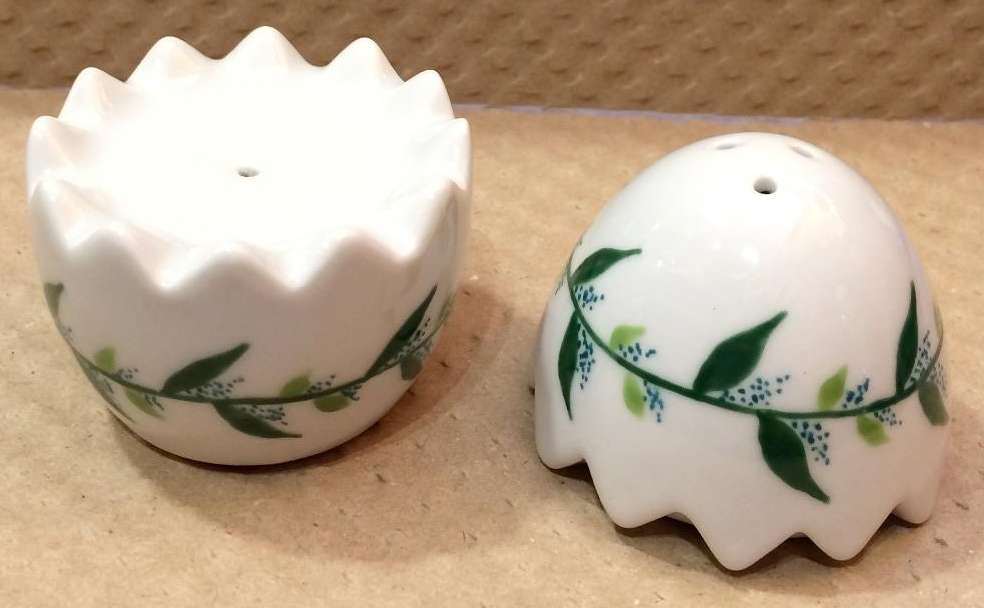 Sel et poivre en porcelaine en forme d'oeuf personnalisé par une frise de feuilles.